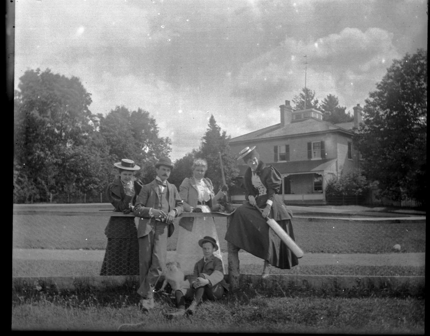 Group of people holding cricket bats in a field at the Patteson family estate in Eastwood, Ontario. Taken in 1890s.