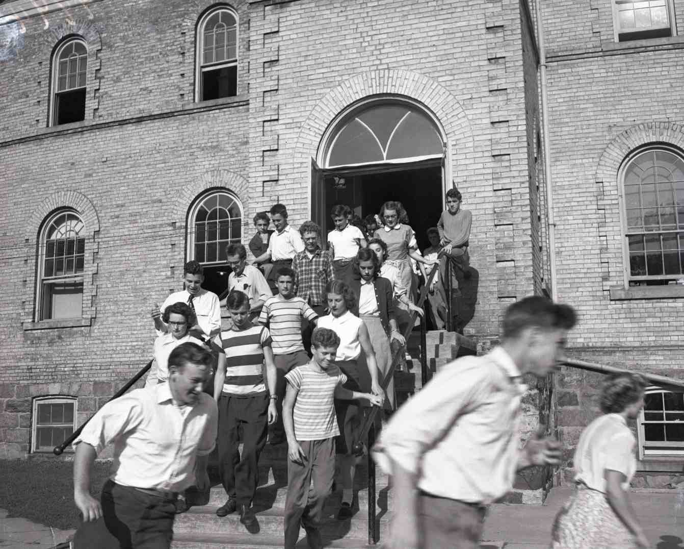 A group of students running out of a school building.