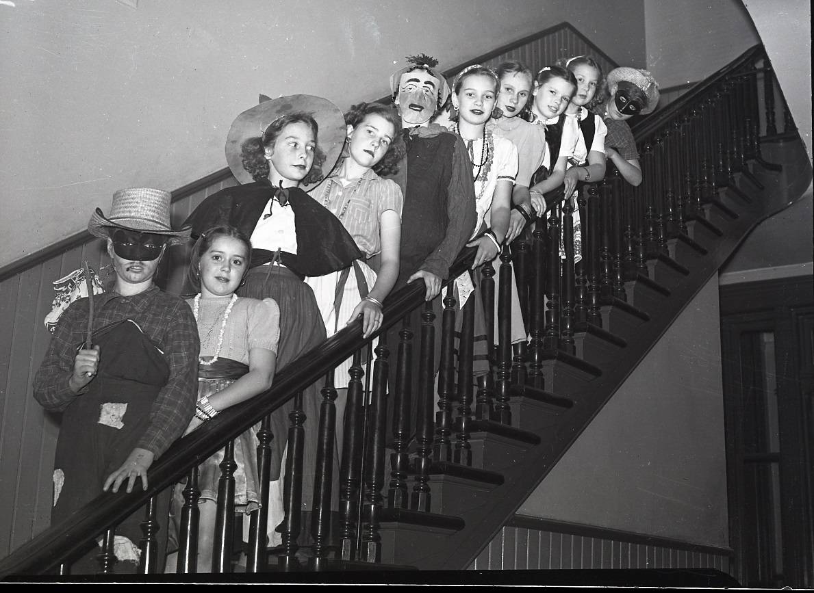 A photograph of students in costume at Central Public School. Some of the children are wearing masks and hats, the female students are wearing skirts and beads.