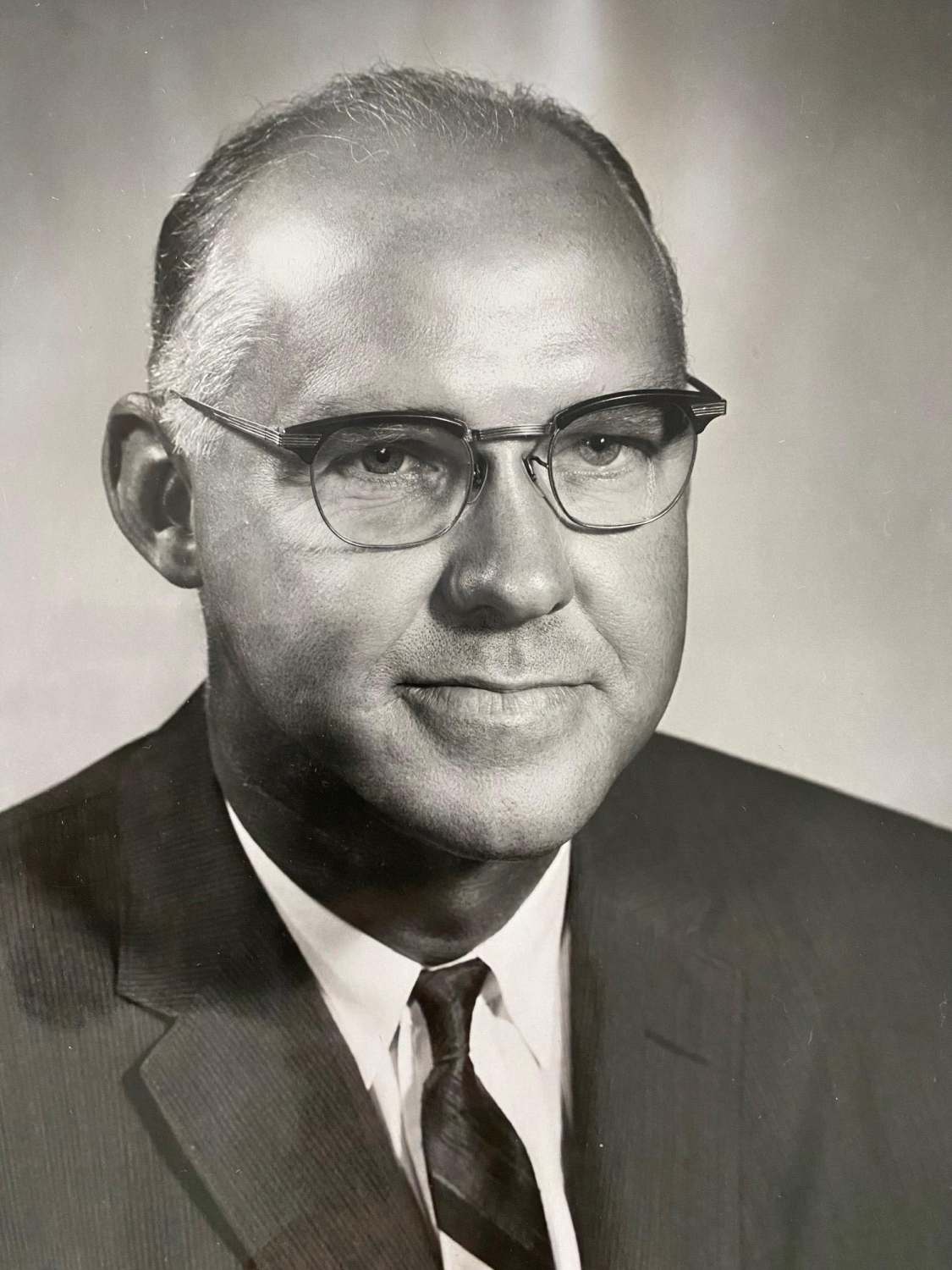 Portrait of Ed Bennett wearing a suit and glasses.