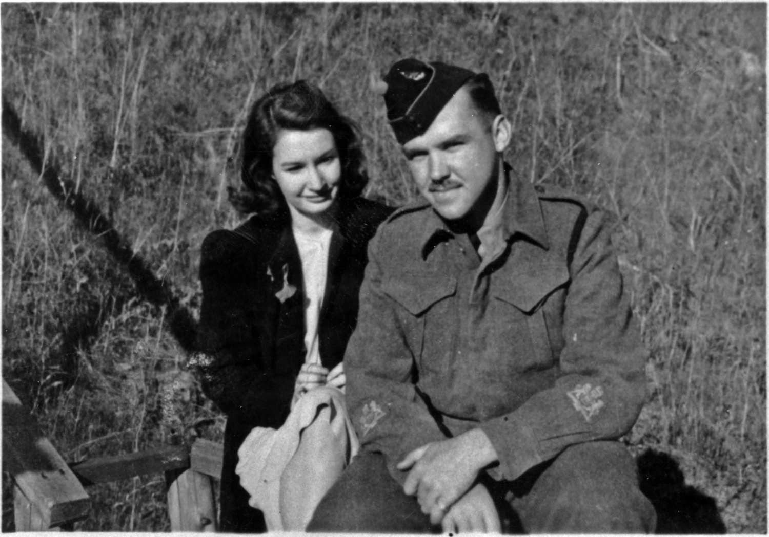 Ed Bennett in his military uniform with his wife Lee sitting in grass.