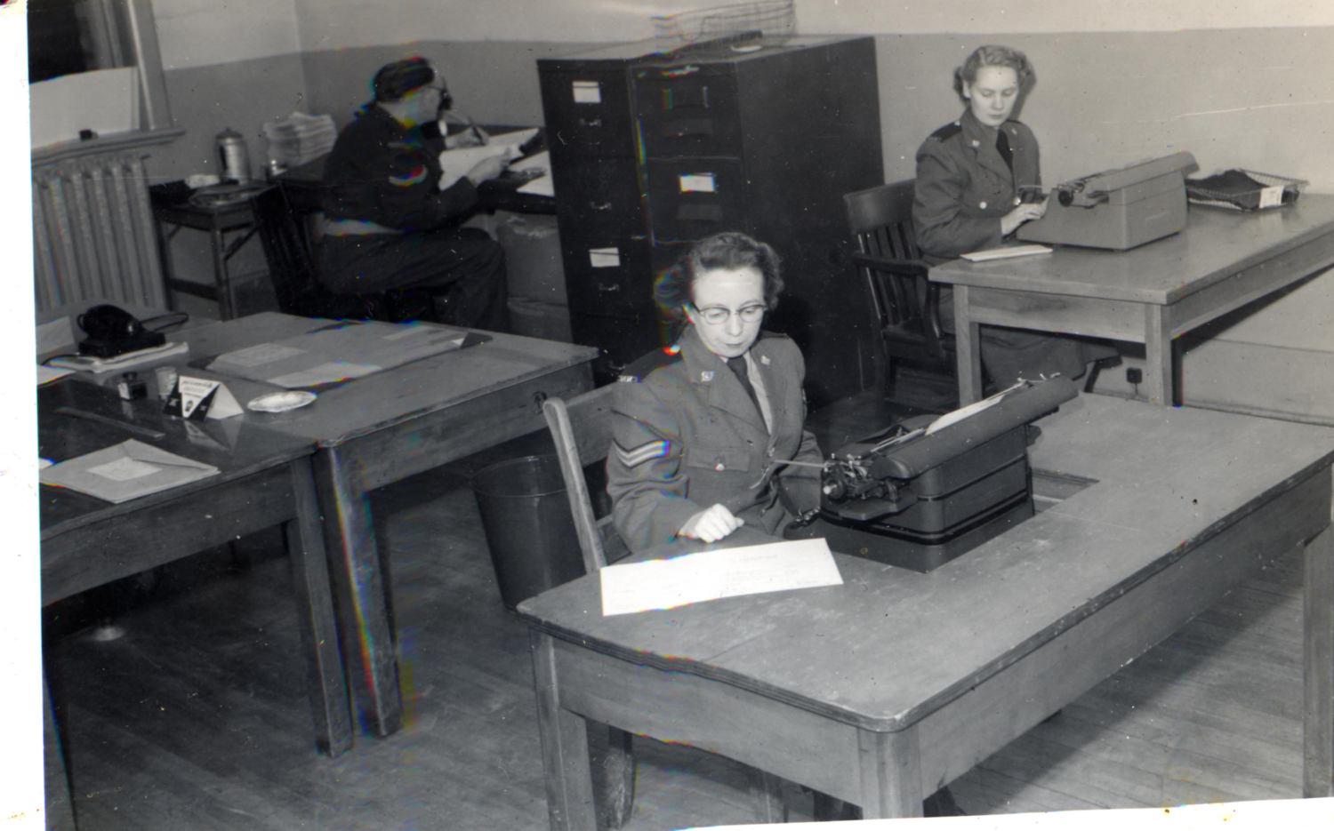 Women in uniform sitting at desks.