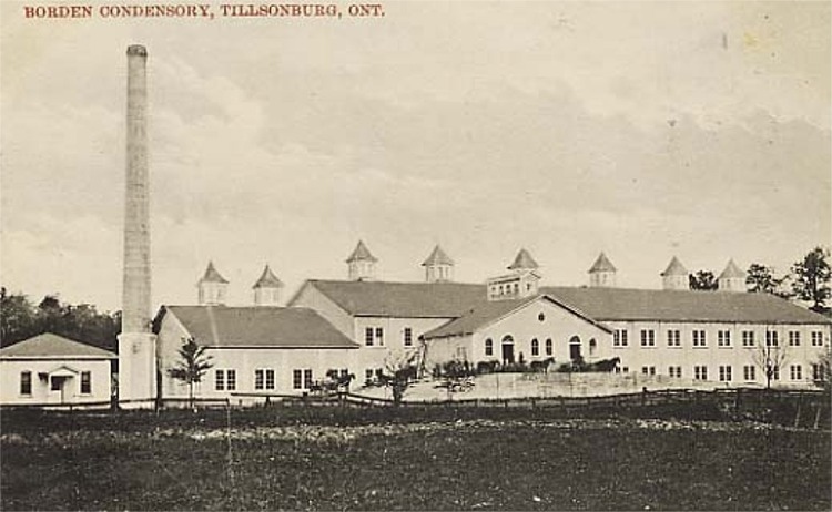 Photograph of Borden Milk Condensory factory in Tillsonburg. Long two-storey building with many windows and a tall smokestack.