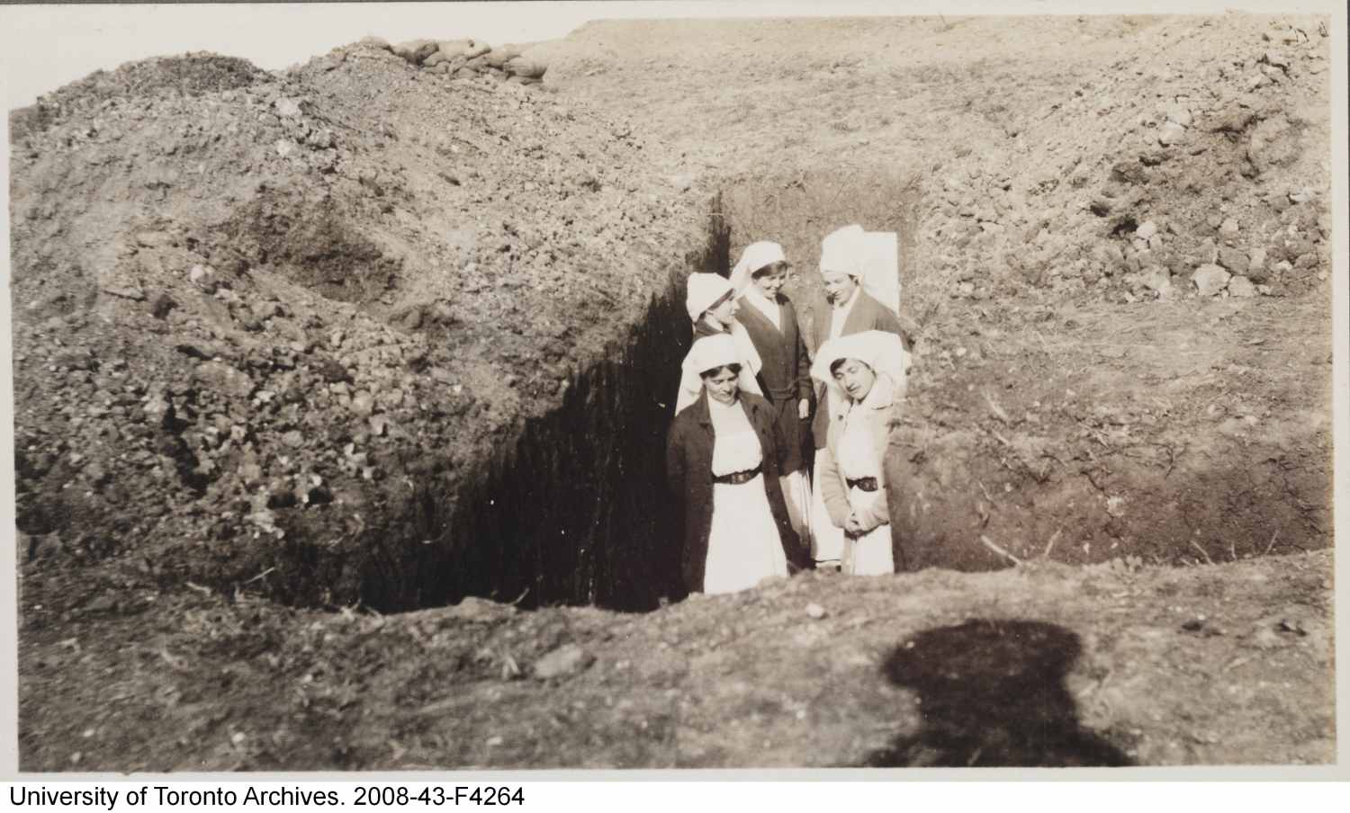 Nursing sisters in uniform posing in a trench.