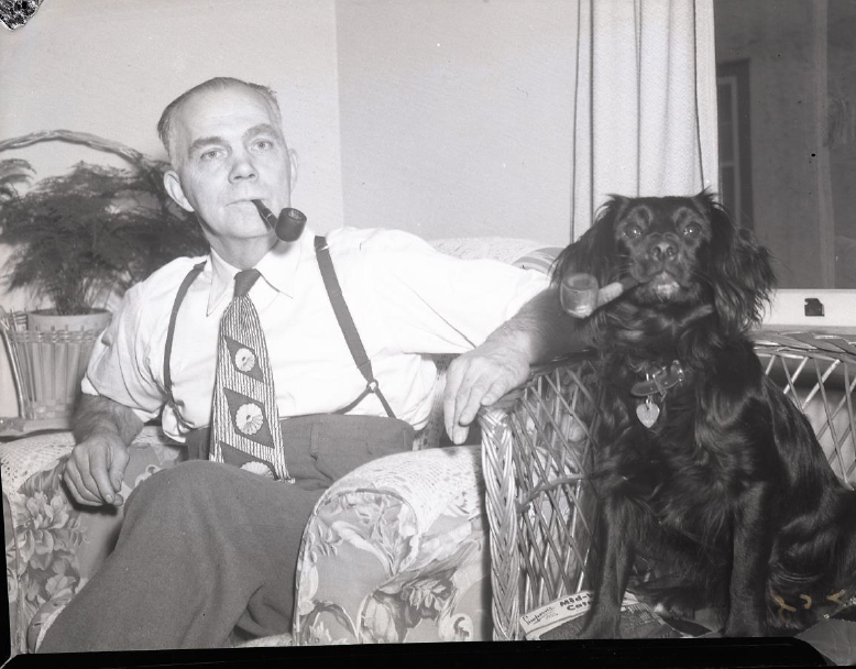 Man and dog sitting in chairs smoking pipes (COA123 8-172)